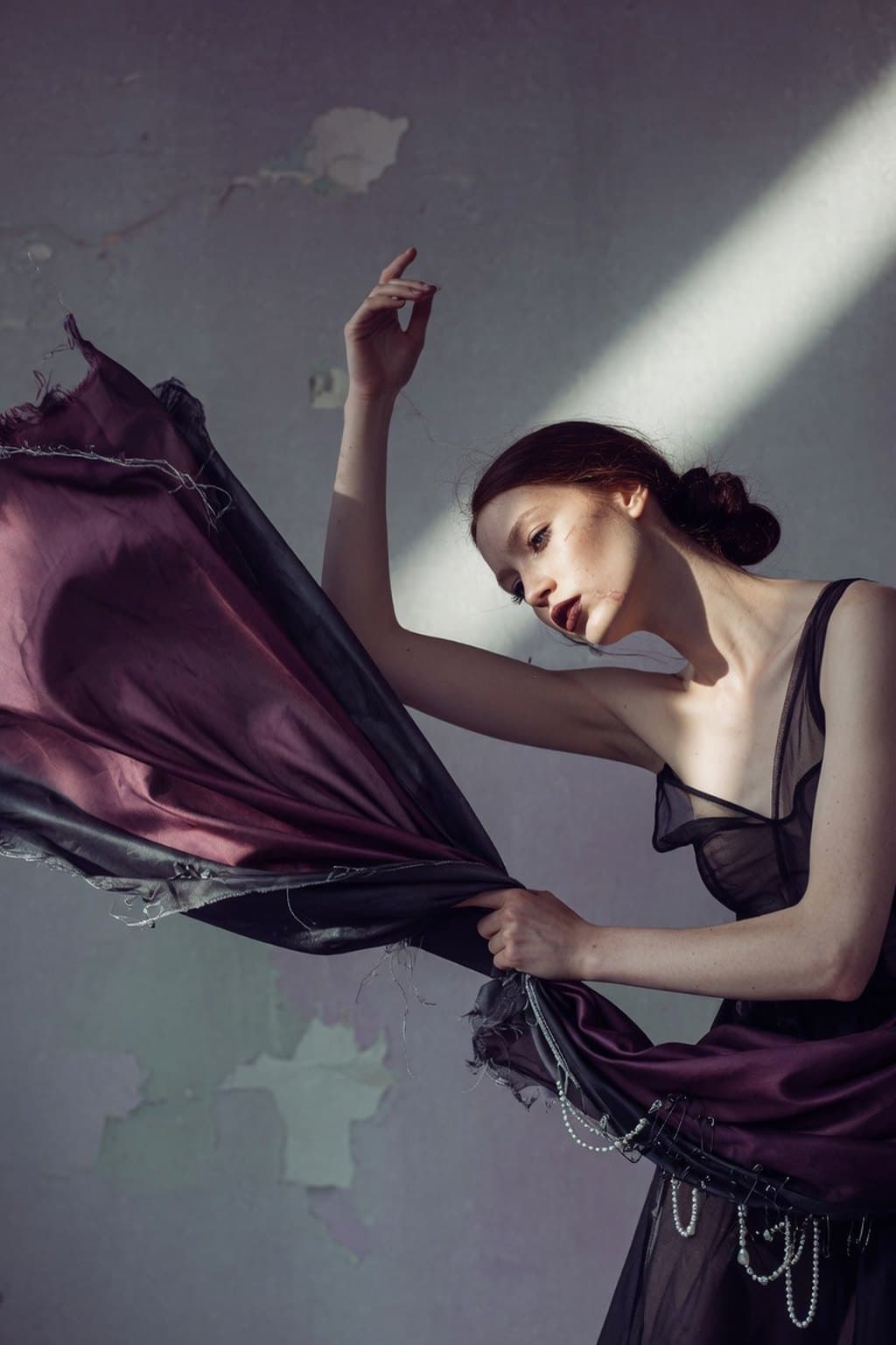 Dark silk caught mid-movement against a raw plaster wall under a hard diagonal of light - rendered by McLeuker AI