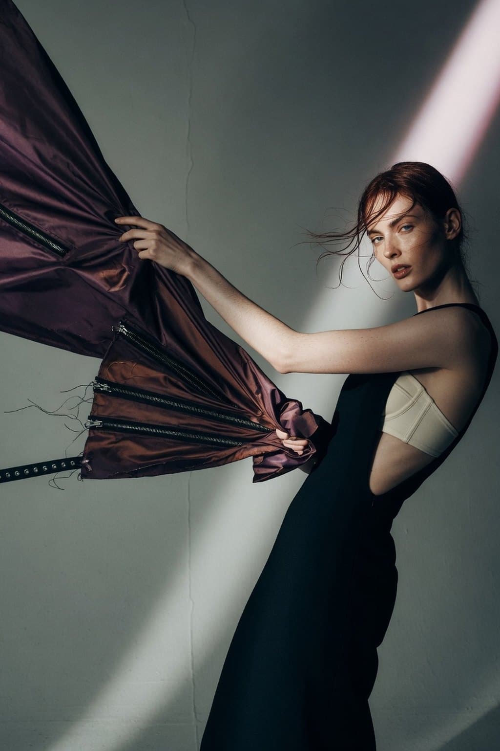 Dark silk caught mid-movement against a raw plaster wall under a hard diagonal of light - rendered by McLeuker AI