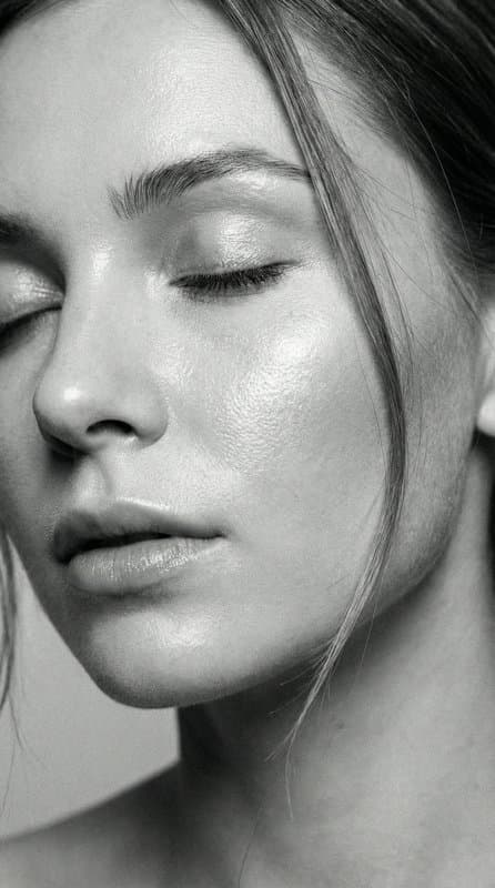 A close portrait with eyes closed and light raking across bare skin